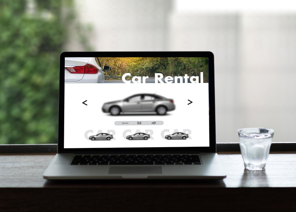 A laptop on a table showing a rental car.